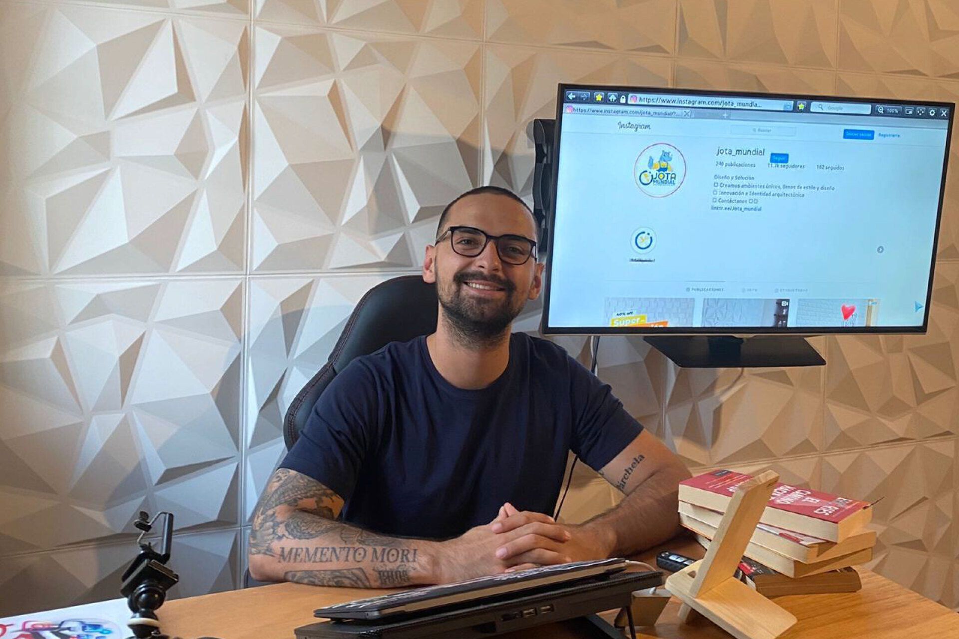 Un hombre está sentado en un escritorio frente a un monitor de computadora.