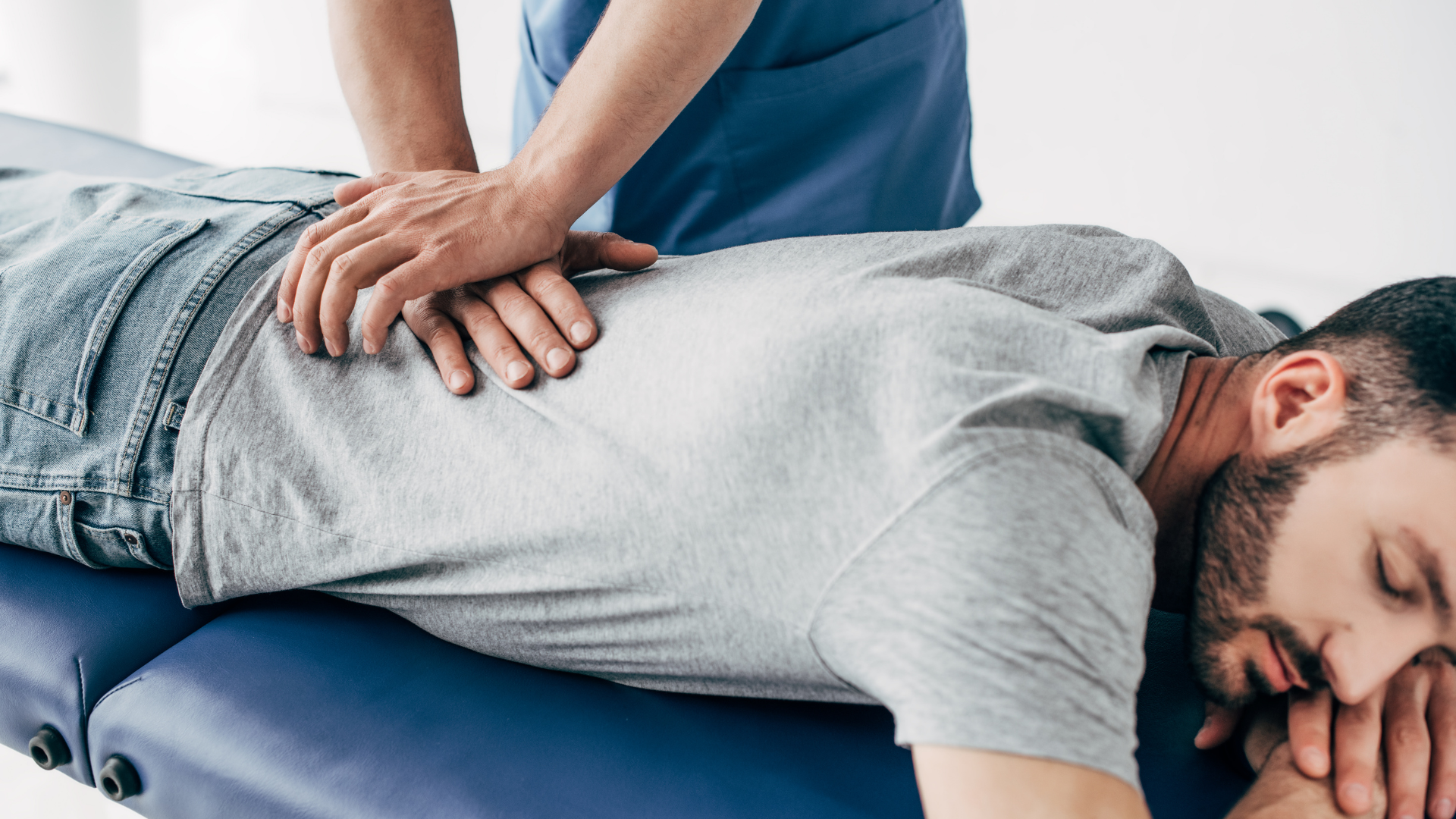 Chiropractor adjusting a patient on a treatment table in a bright office.
