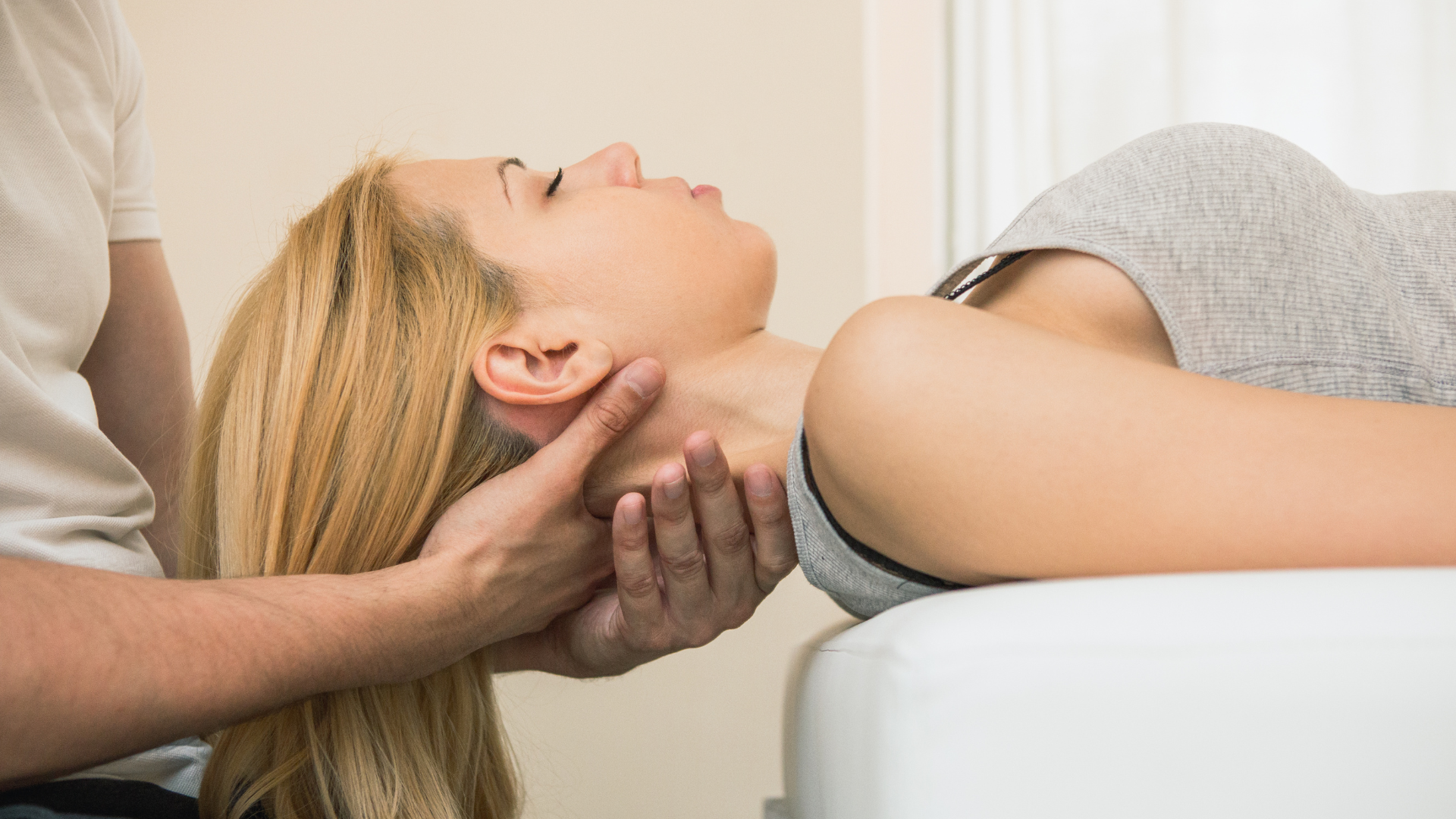 Person receiving a neck massage while lying on a treatment table, eyes closed