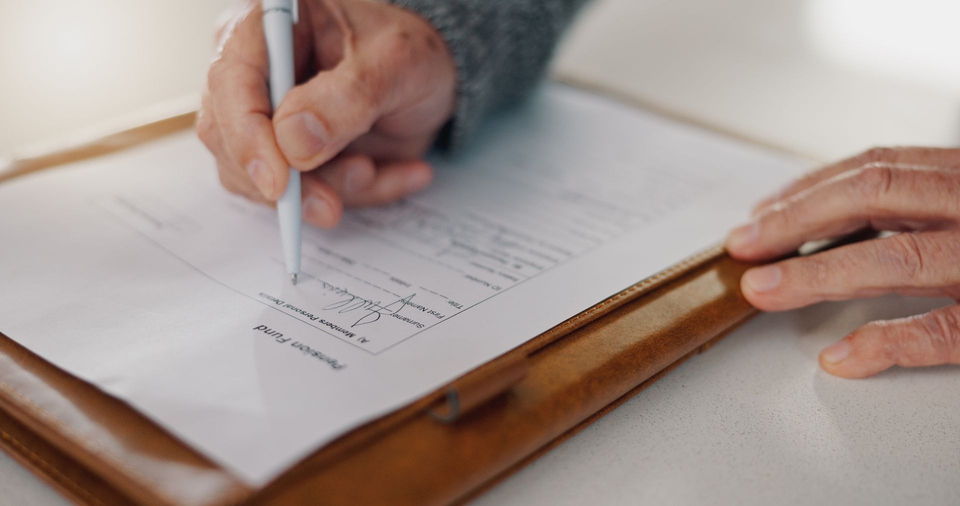 A person is writing on a clipboard with a pen.