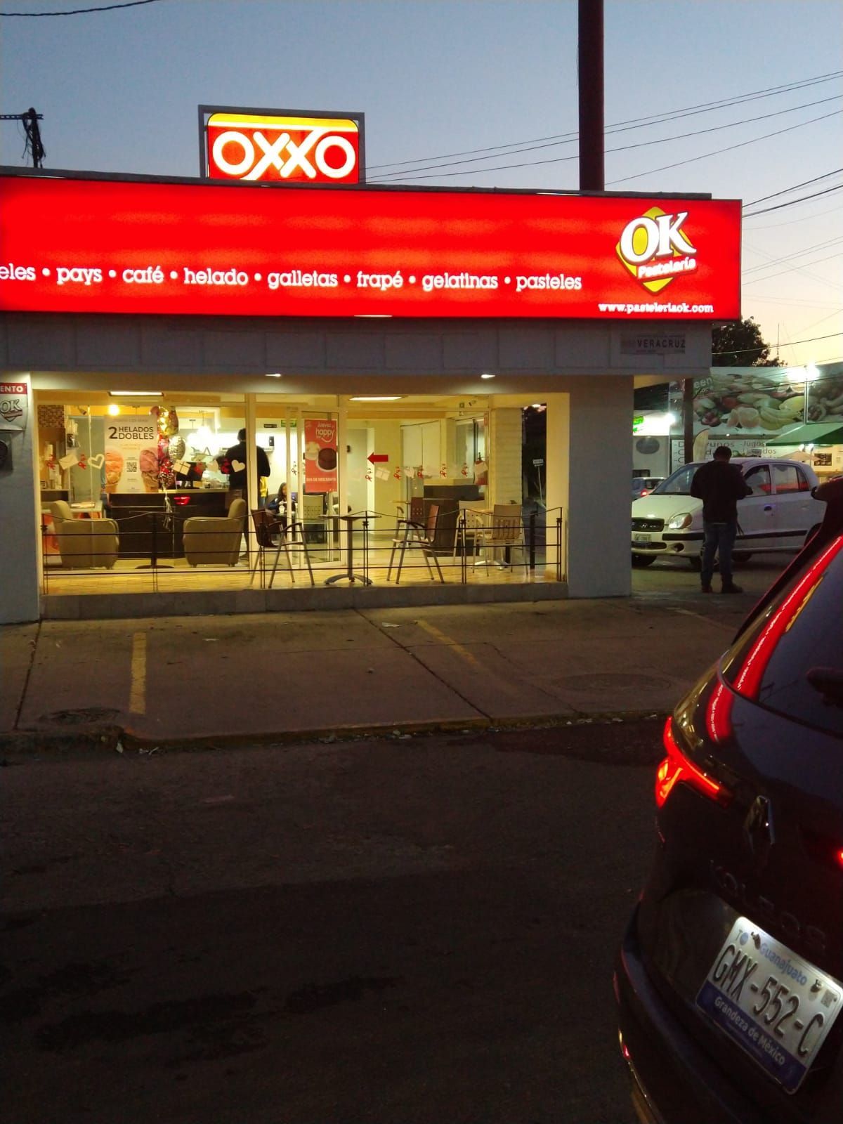 Un coche está estacionado frente a una tienda Oxxo.