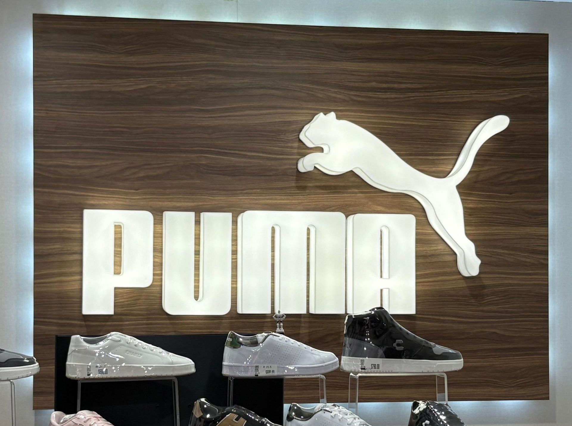 Una exhibición de zapatos frente a un cartel de Puma.