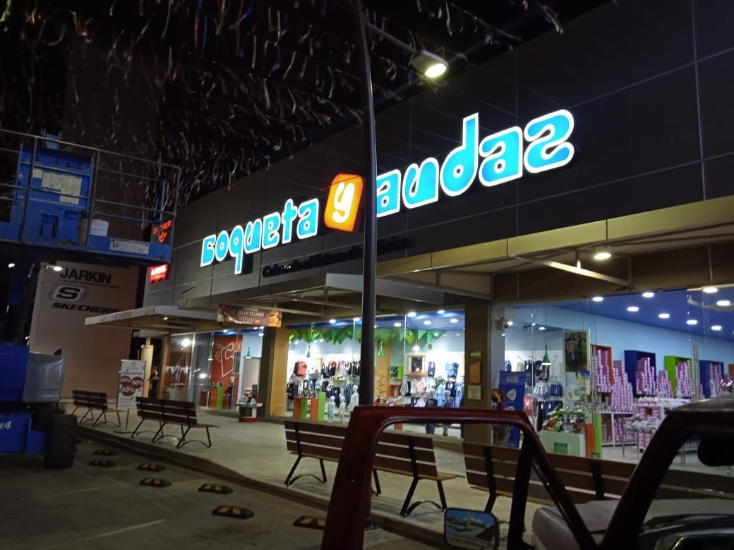 Una tienda con un coche aparcado delante por la noche.