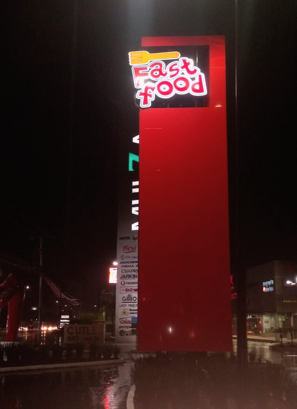 Un cartel de comida rápida está iluminado por la noche.