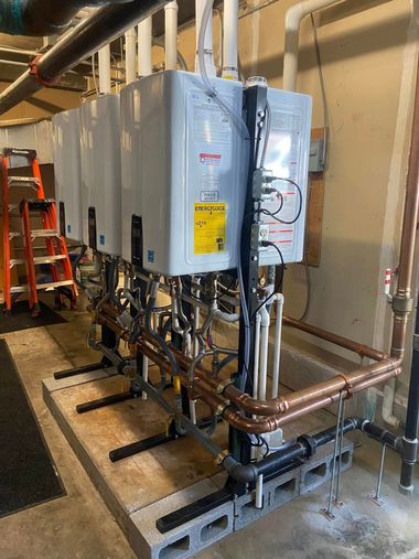 Industrial HVAC units and copper piping mounted along a wall in a utility room.