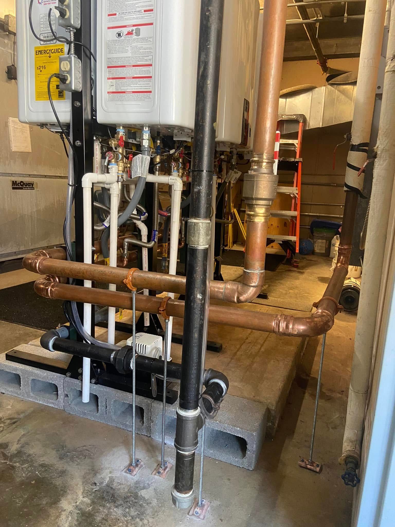 Industrial boiler room with pipes, valves, and a water heater on a concrete platform.