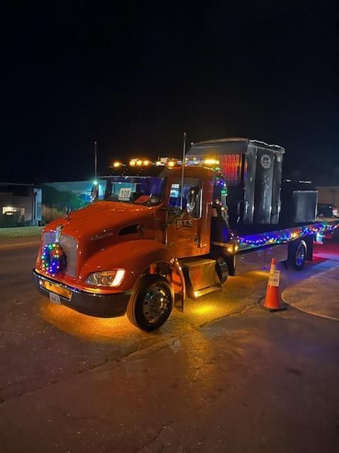 A white garbage truck is parked in a gravel lot.