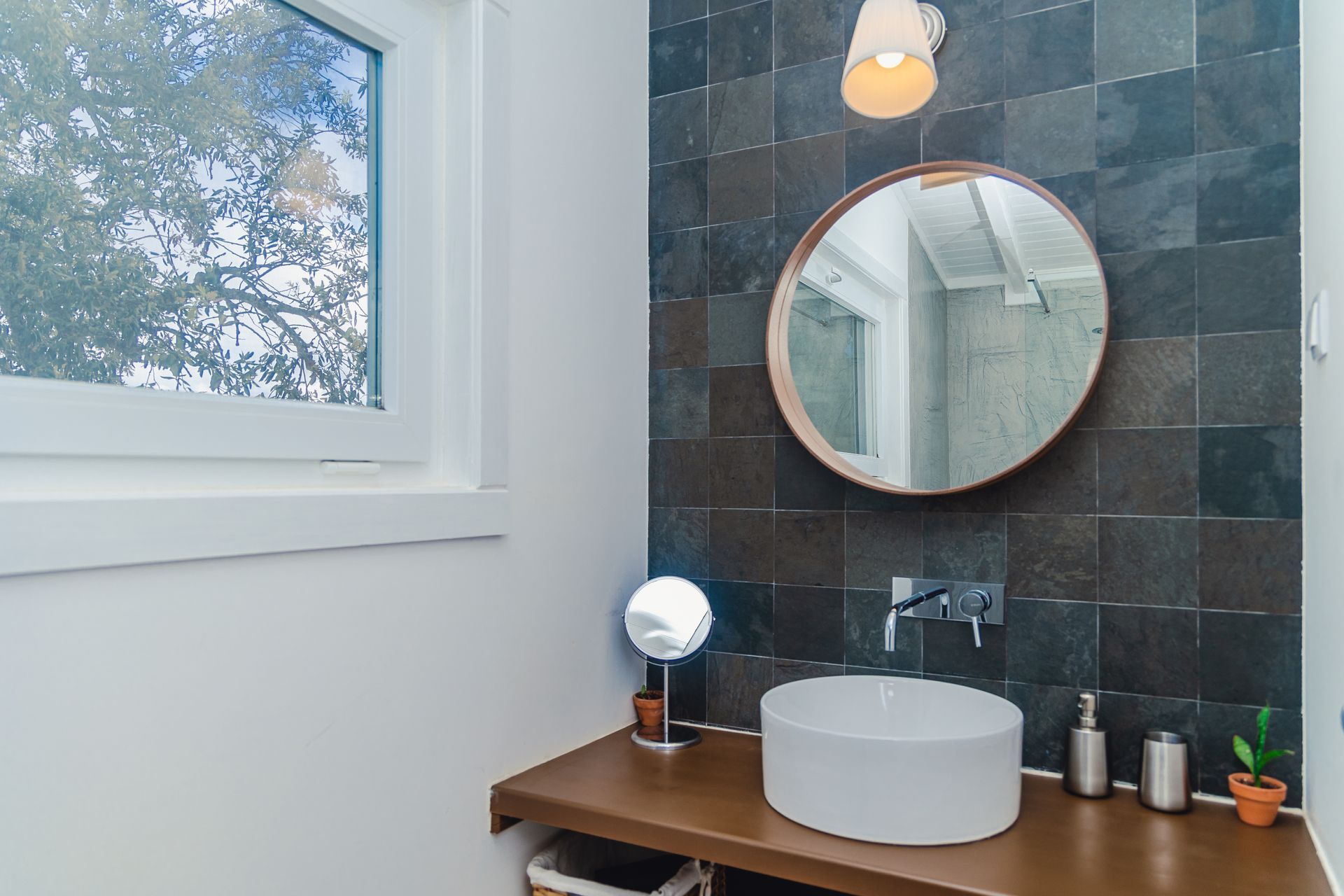 A bathroom with a sink , mirror and window.