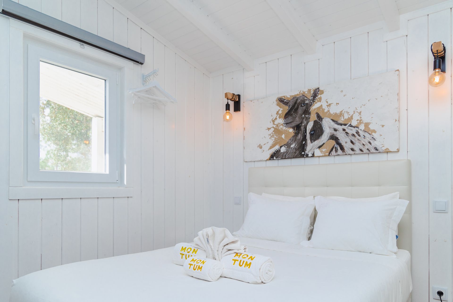 There is a painting of a giraffe on the wall above the bed.