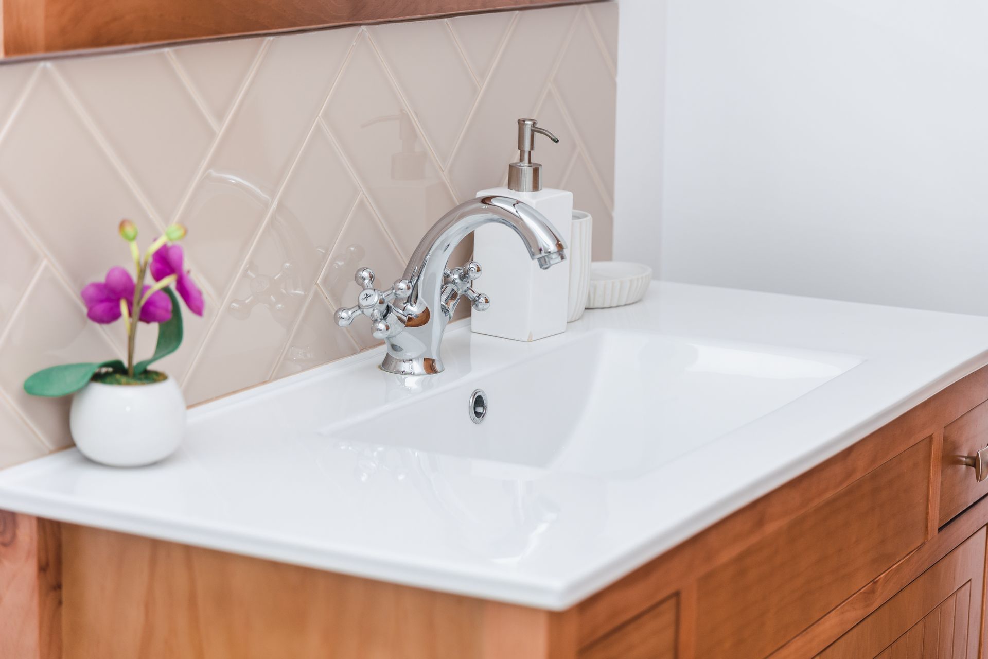 A bathroom sink with a faucet and a vase of flowers on it.