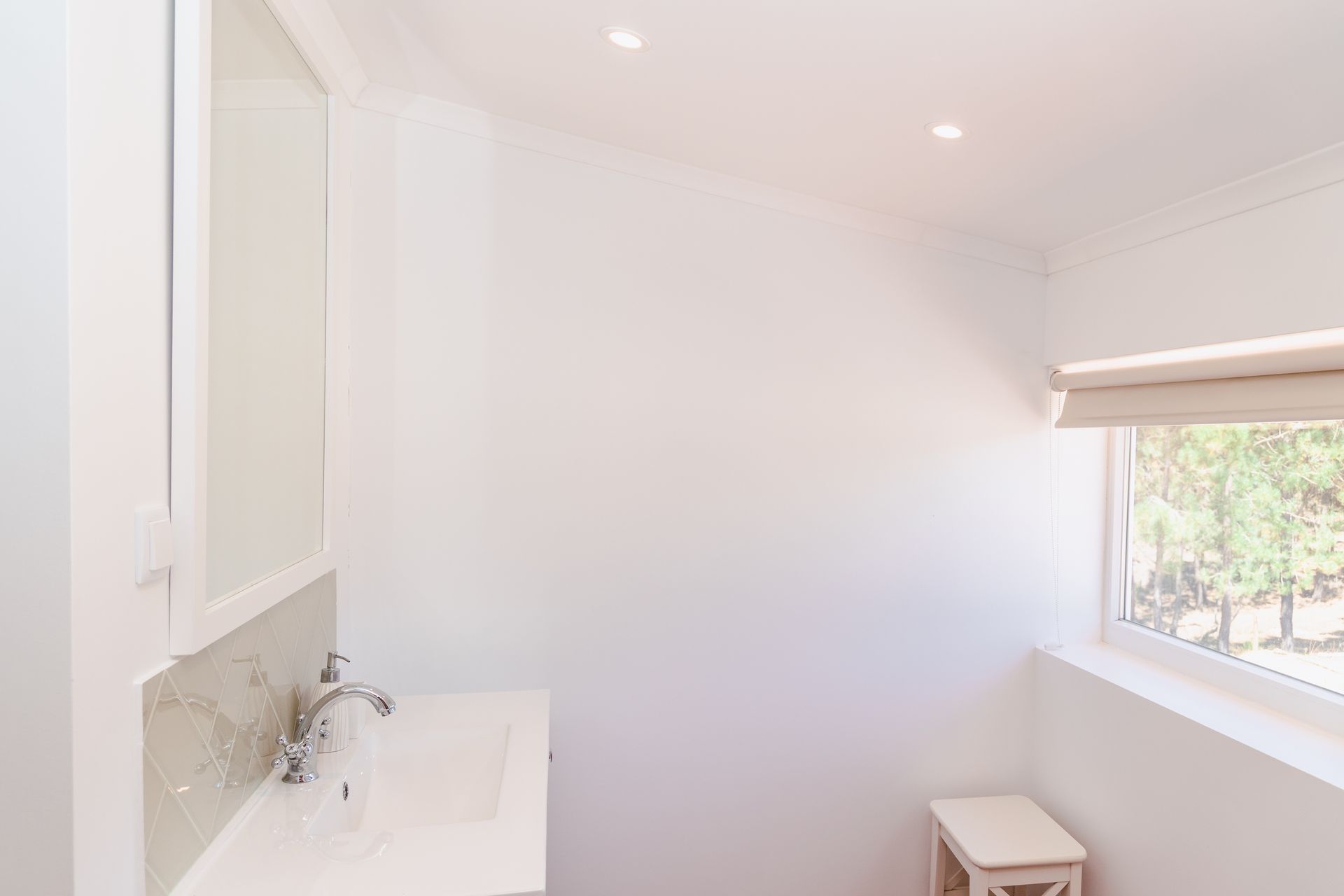 A bathroom with a sink , mirror and window.