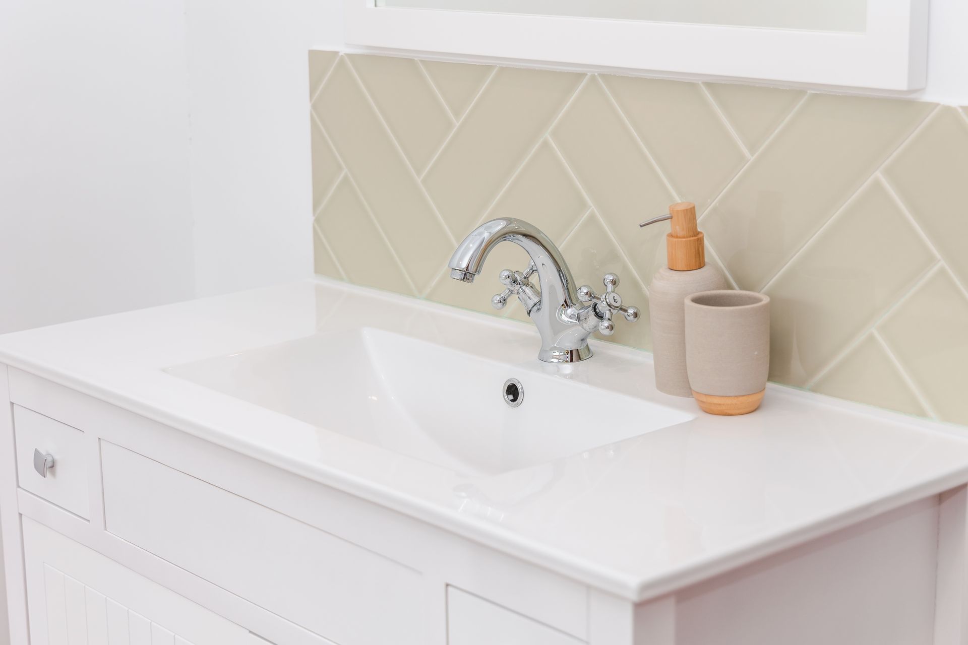 A bathroom sink with a soap dispenser and a cup on the counter.