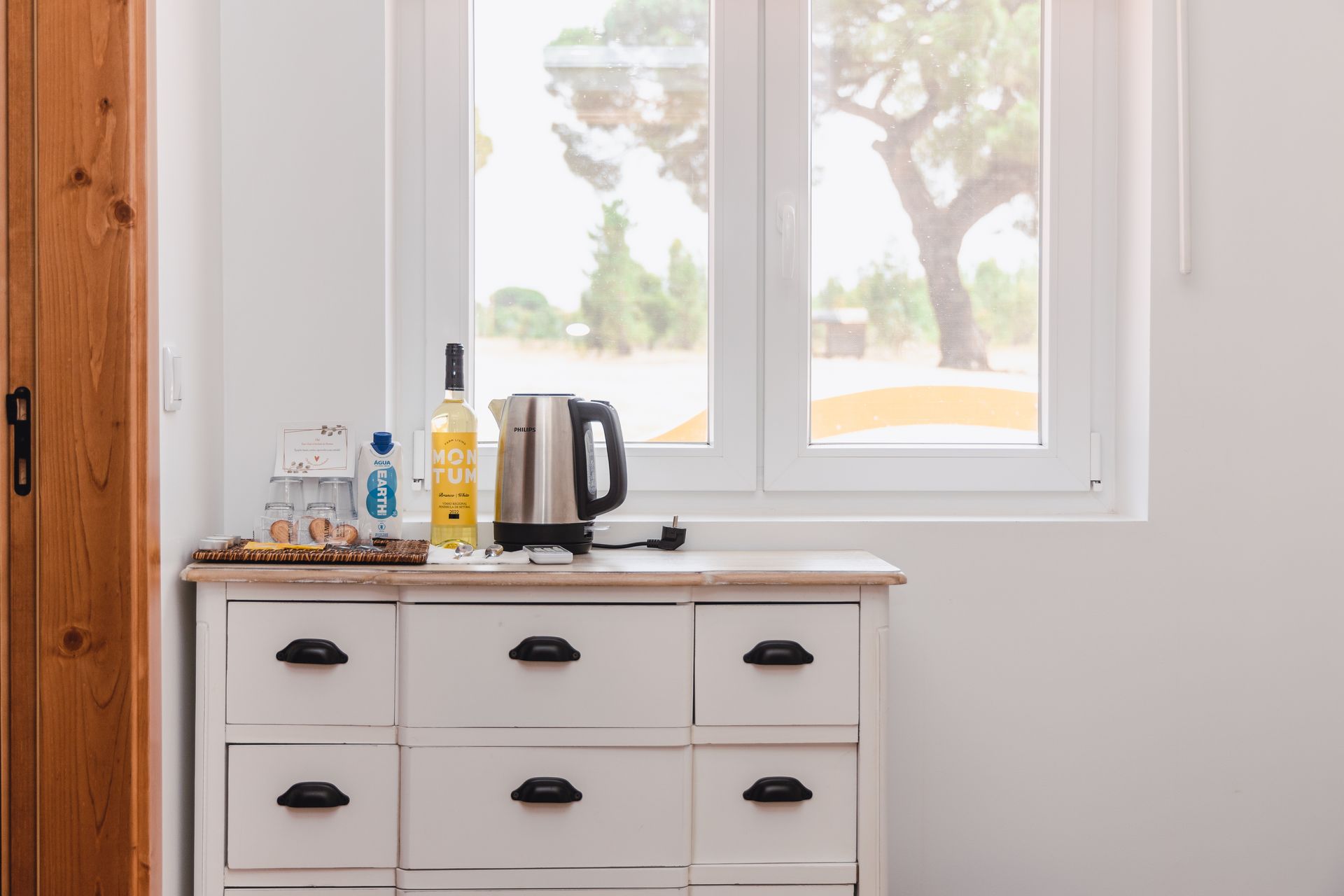 A white dresser with drawers and a window in a room.