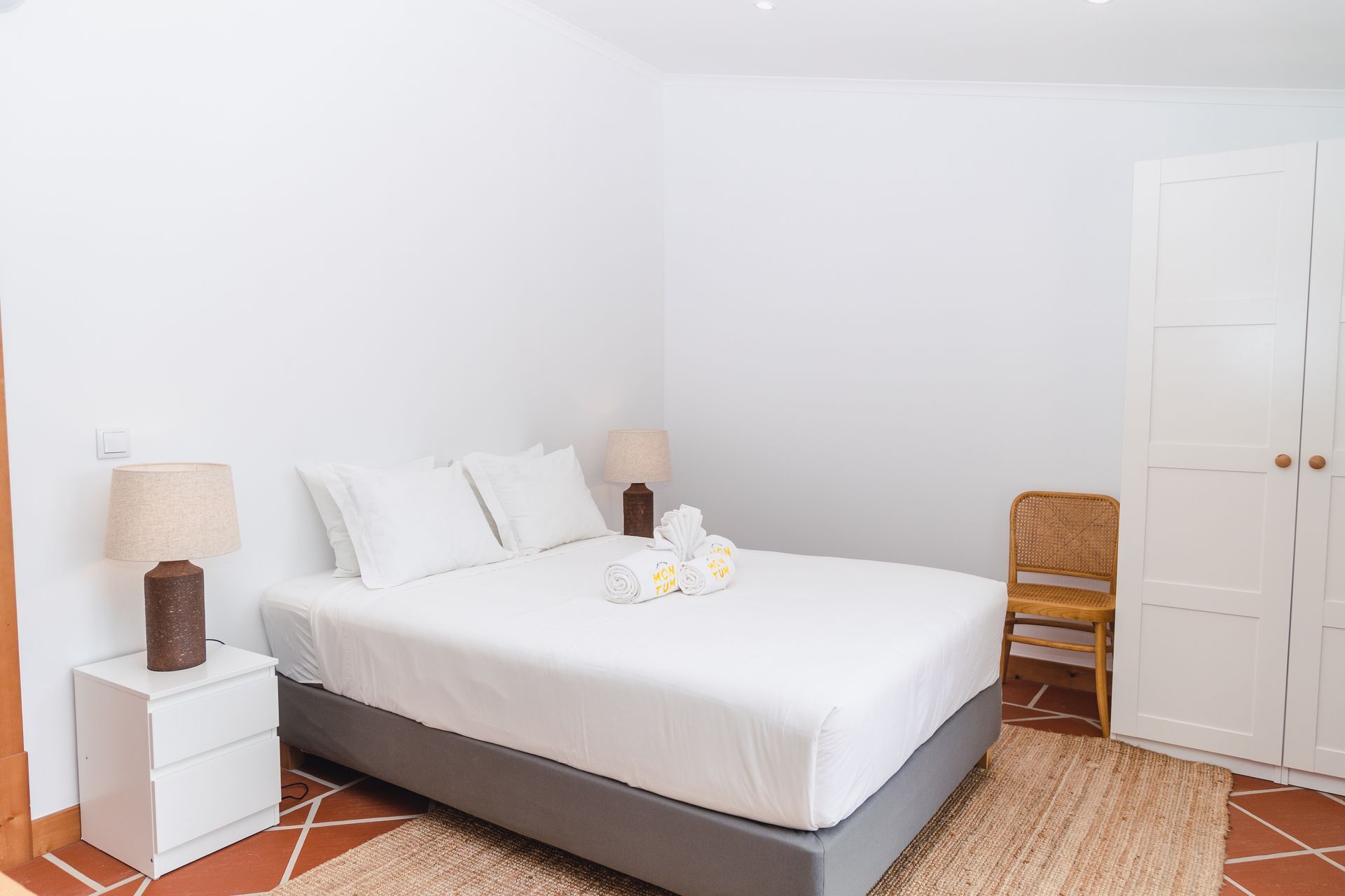A bedroom with a bed , nightstand , lamp and chair.