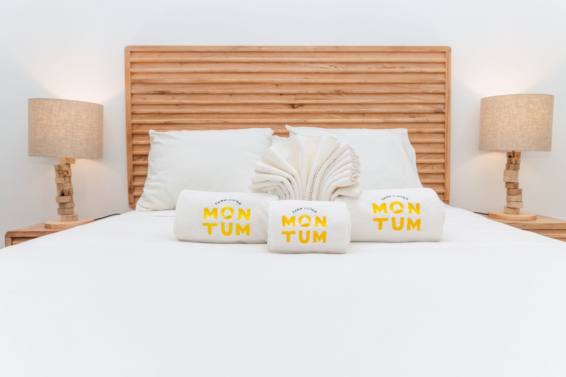 A bed with three towels on it and a wooden headboard.