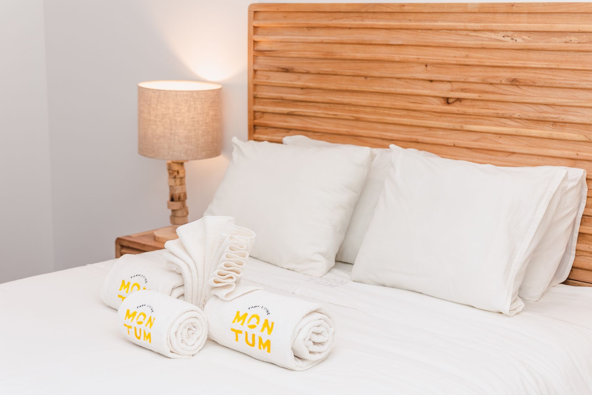 A bed with white sheets and pillows and two towels on it.