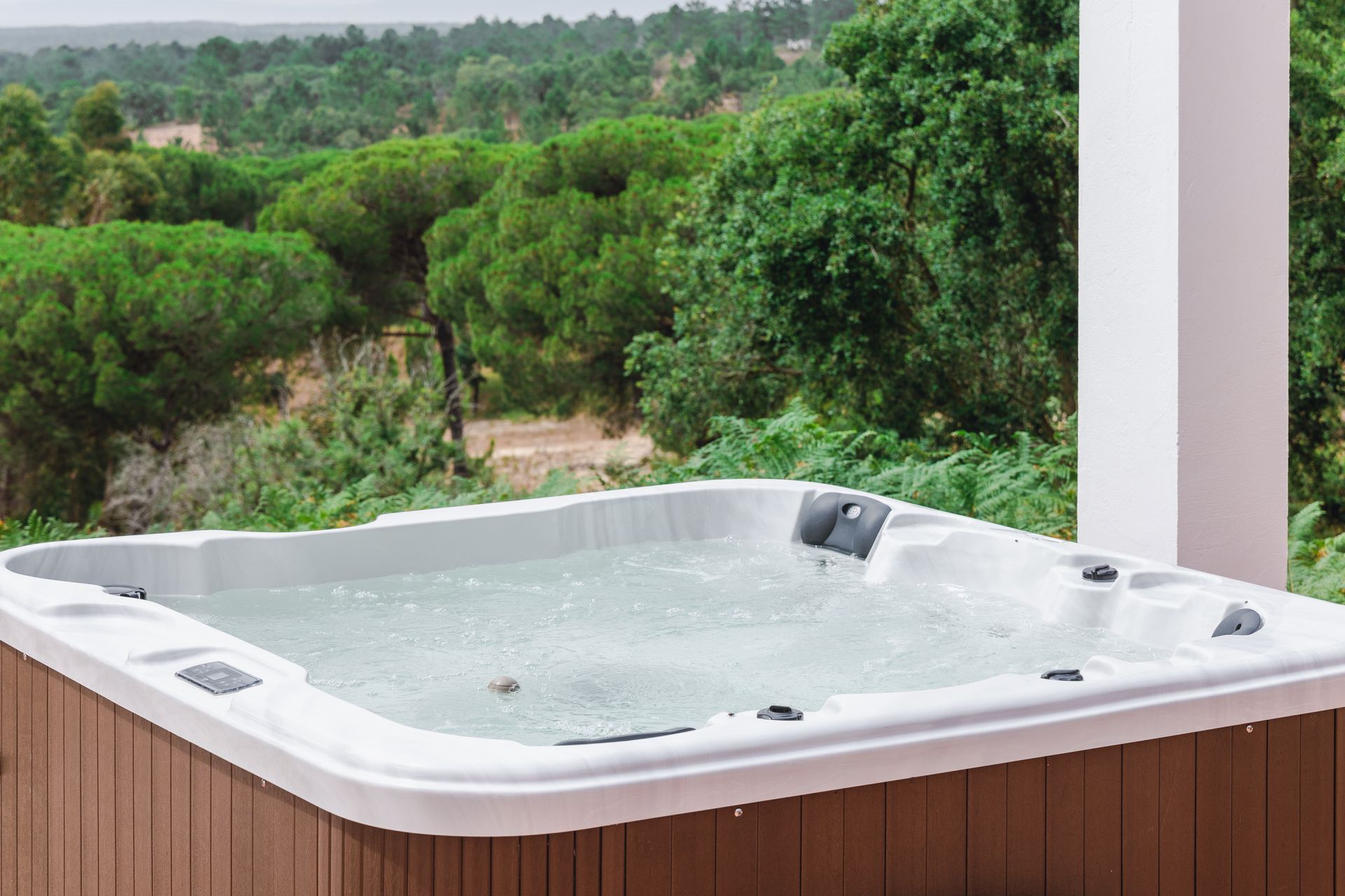 A hot tub is sitting on a porch with trees in the background.
