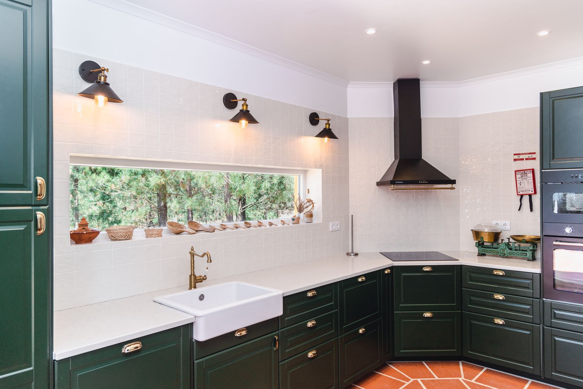 A kitchen with green cabinets , a sink , and a window.