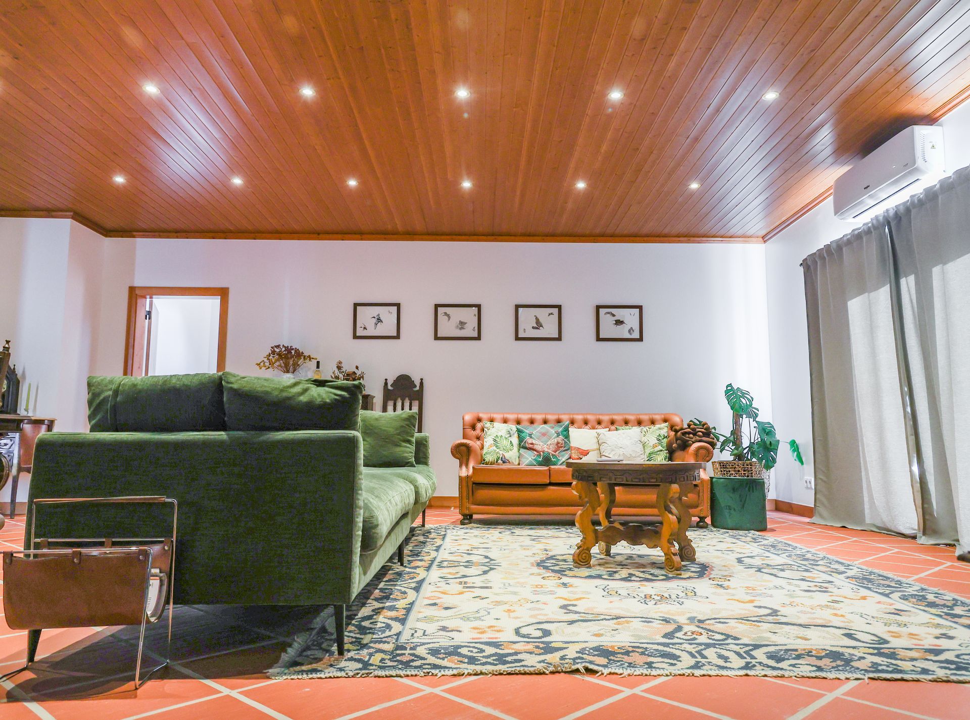 A living room with a green couch and a wooden ceiling.