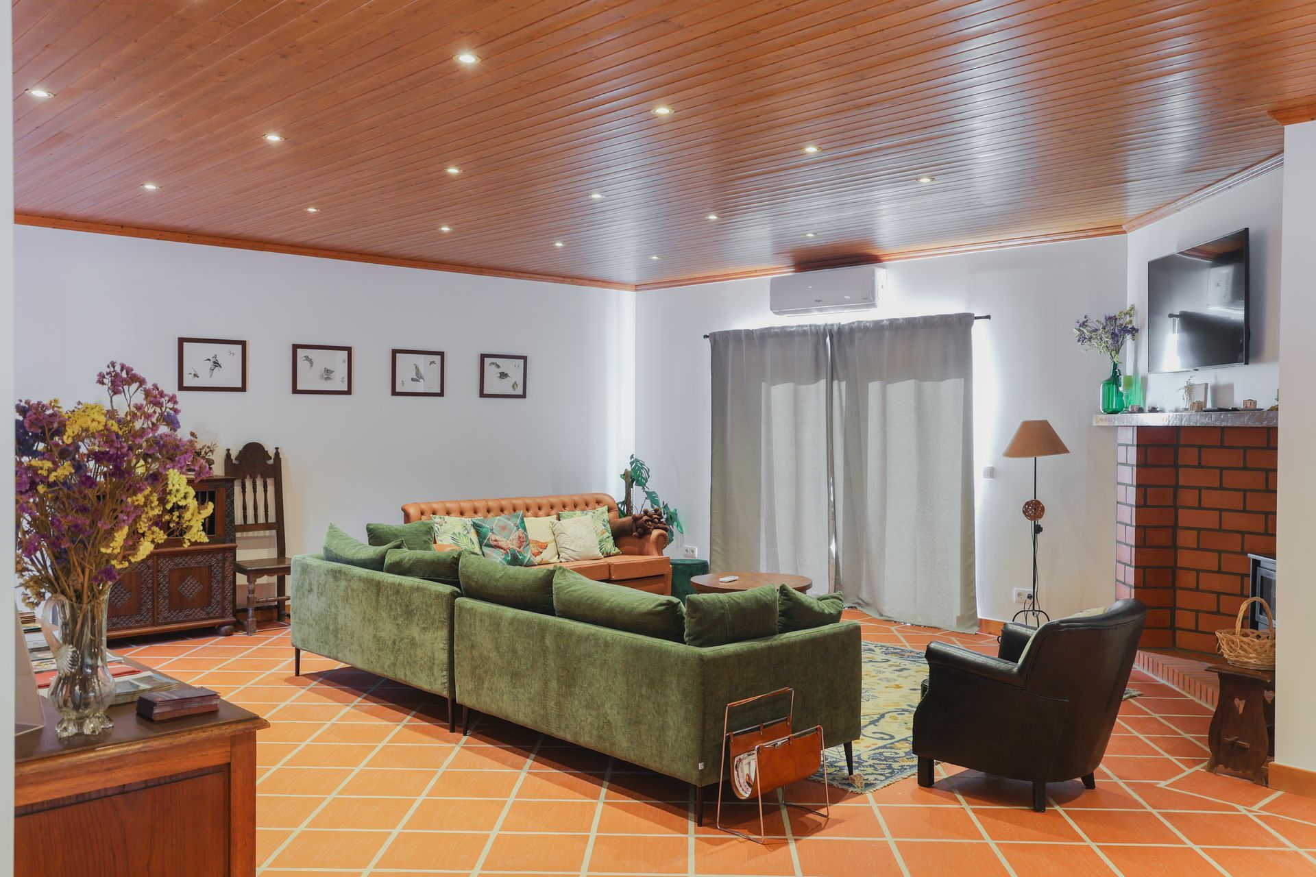 A living room with a green couch , chairs , and a fireplace.