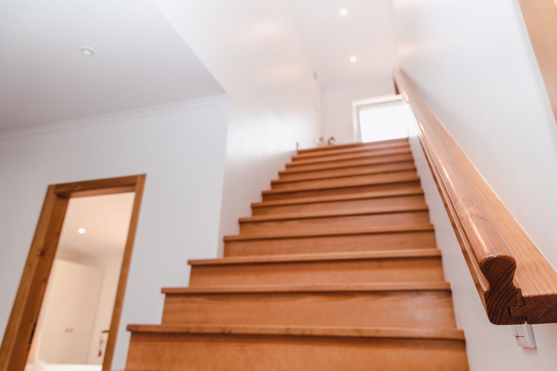 A wooden staircase with a wooden railing leading up to the second floor of a house.
