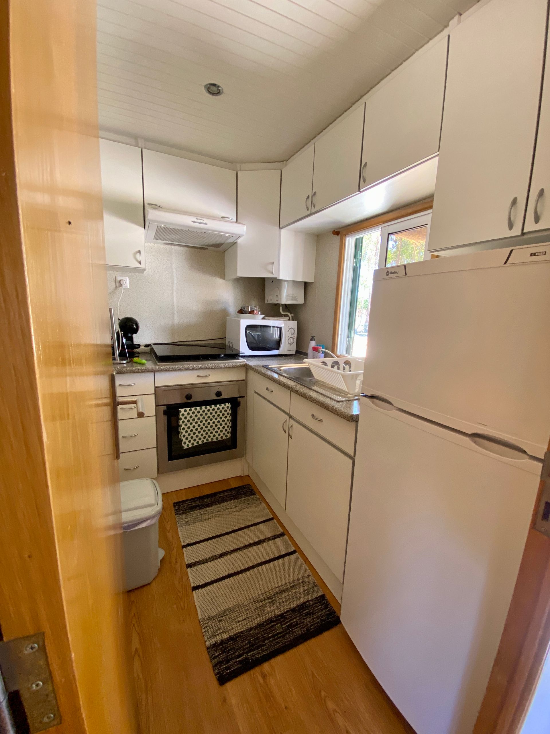 A kitchen with white cabinets , a refrigerator , a microwave , and a sink.