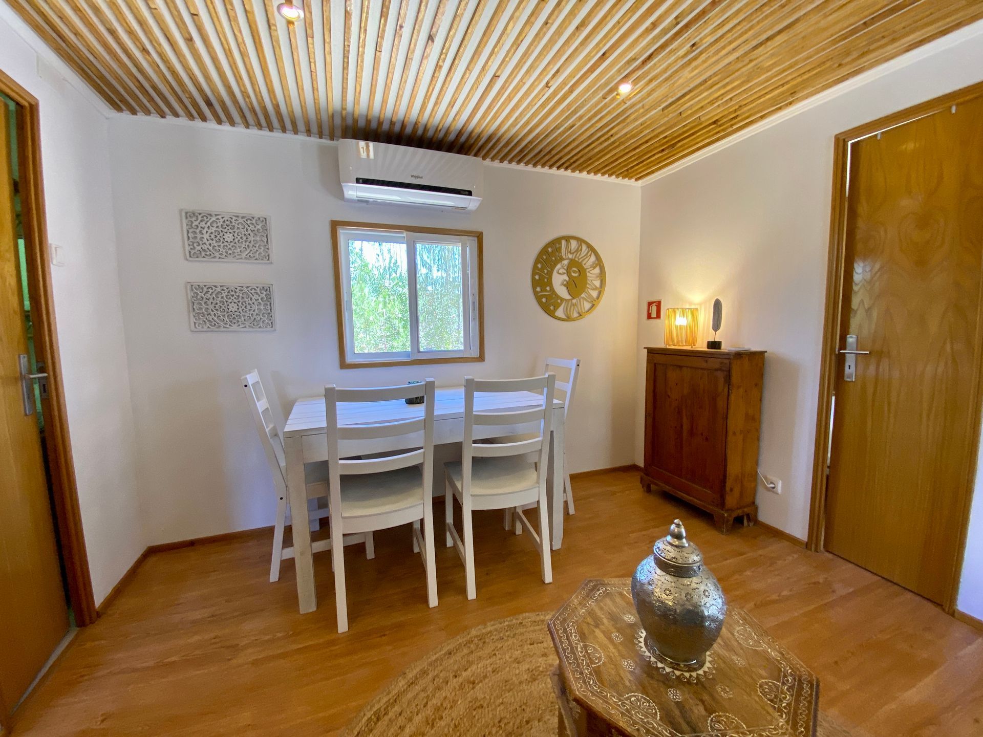 A dining room with a table and chairs and a clock on the wall.