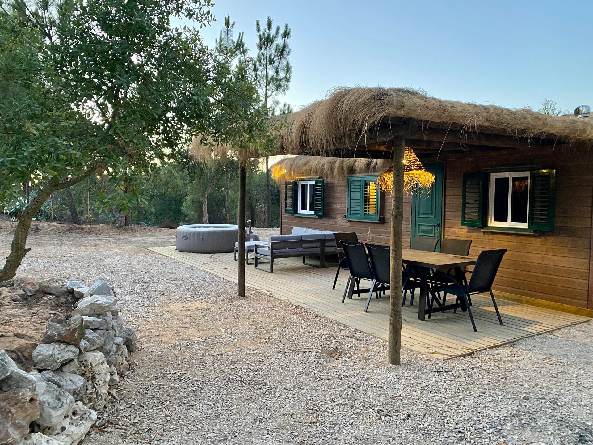 A wooden house with a thatched roof and a table and chairs in front of it.