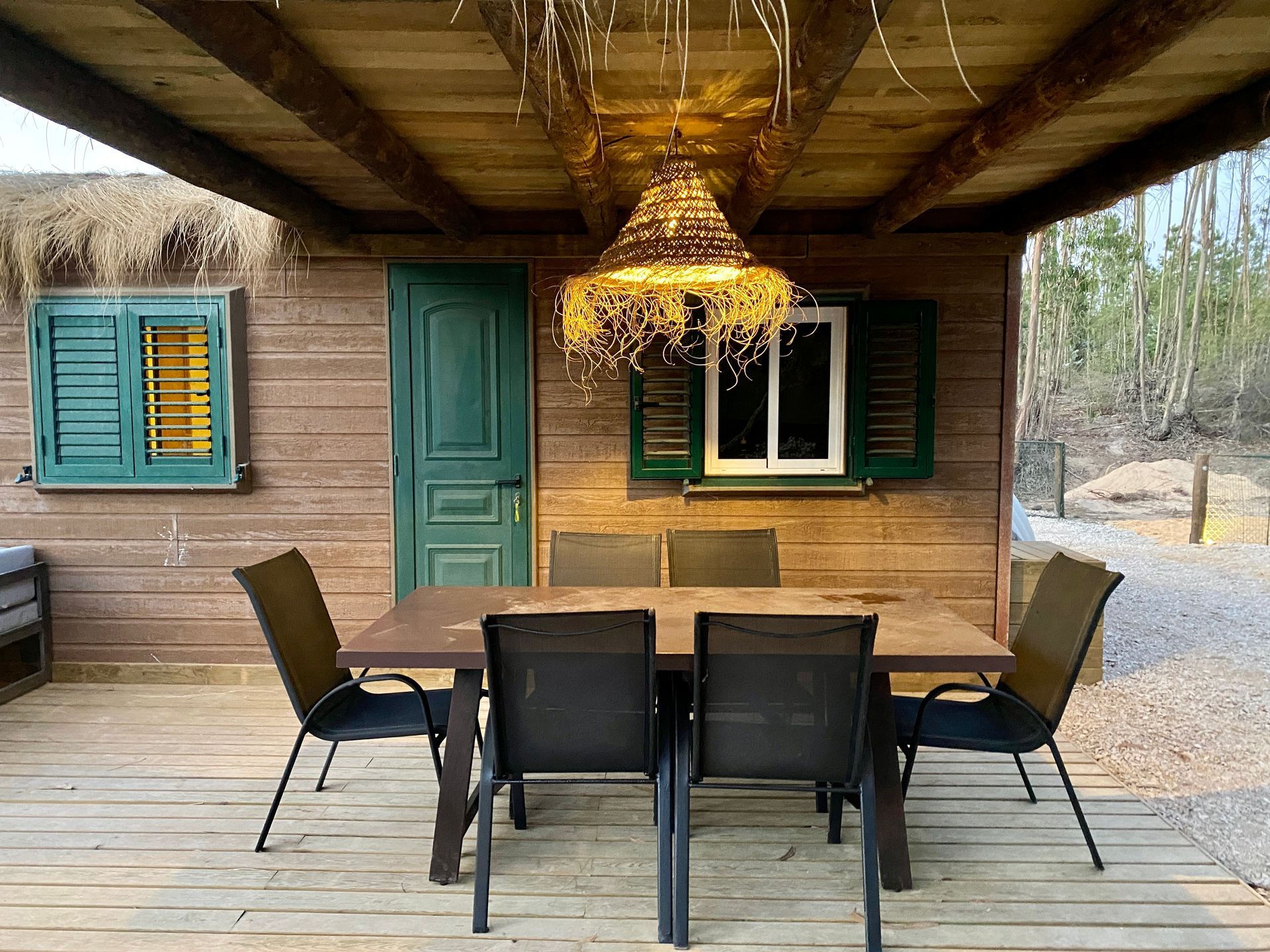 There is a table and chairs on the deck of a wooden house.