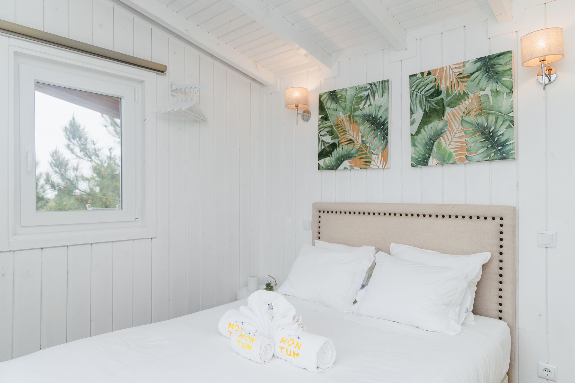 A bedroom with a bed , paintings on the wall and a window.