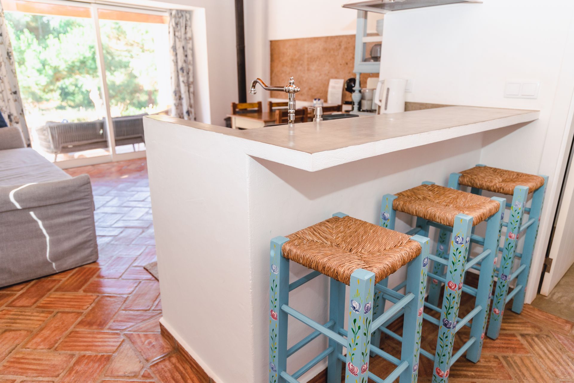 A kitchen with a bar and three wicker stools.