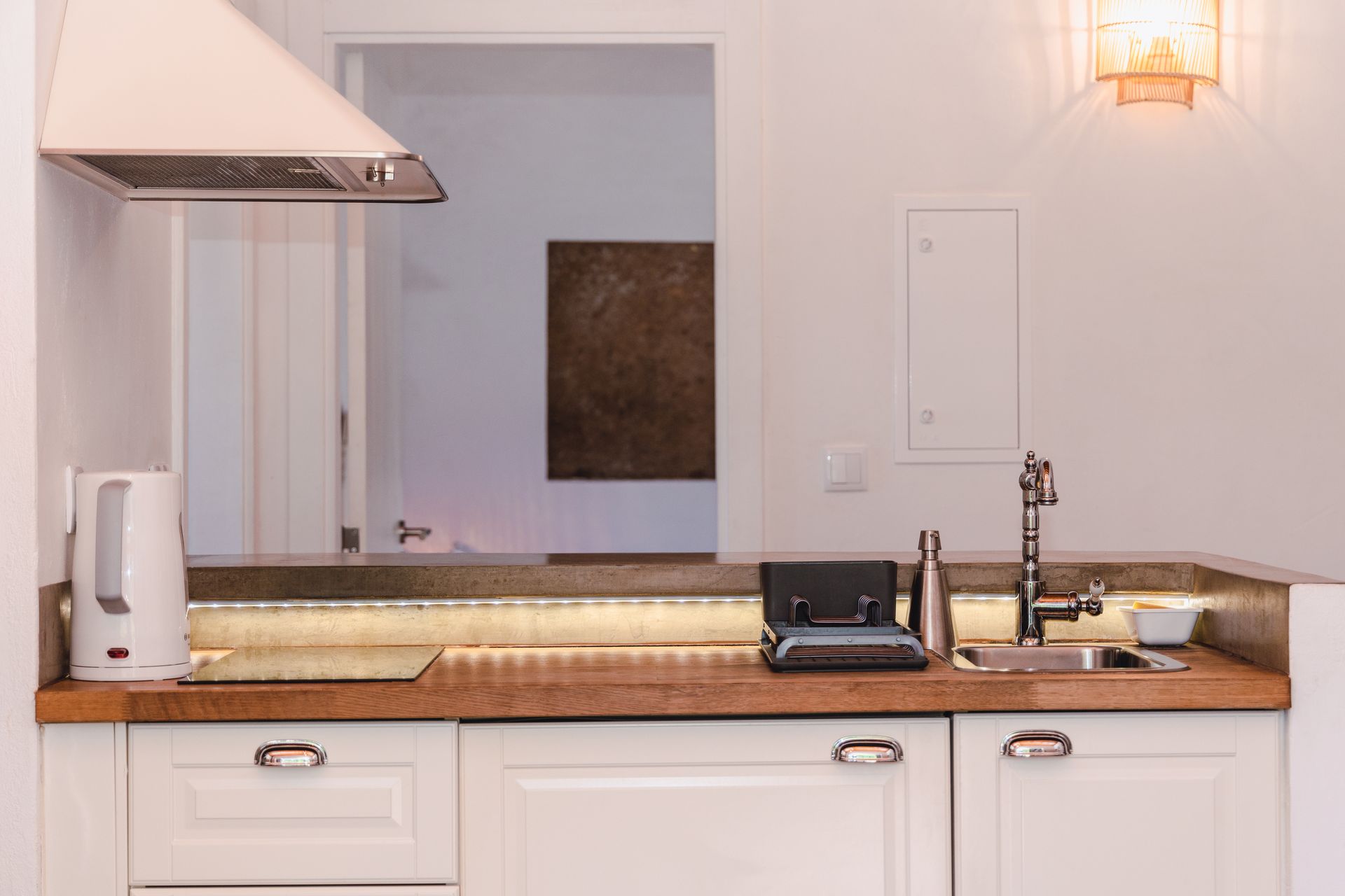 A kitchen with white cabinets , a sink , a stove and a hood.