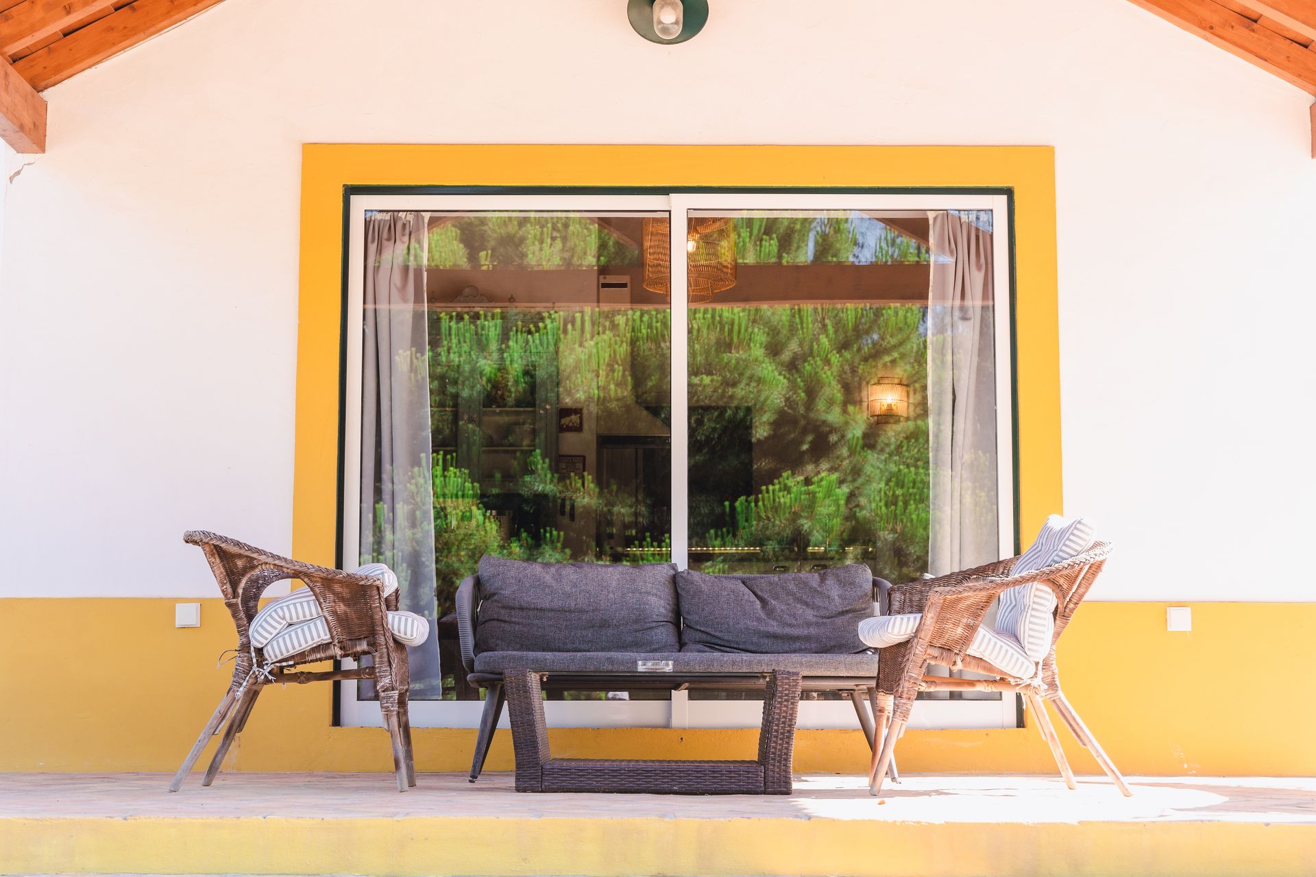 There is a couch and chairs on the porch of a house.