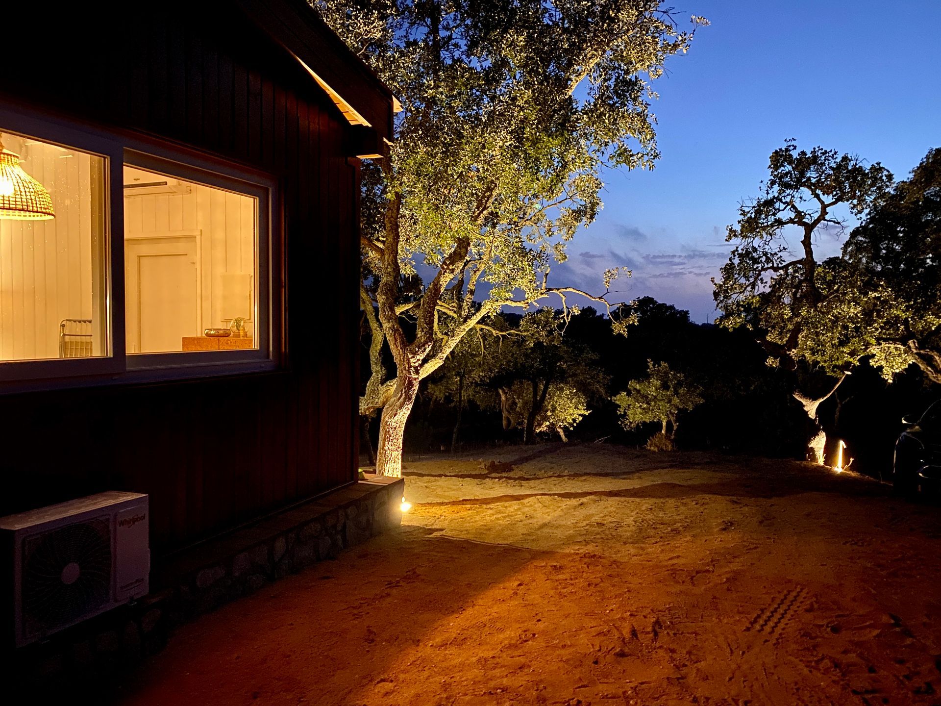 A house is lit up at night with trees in the background