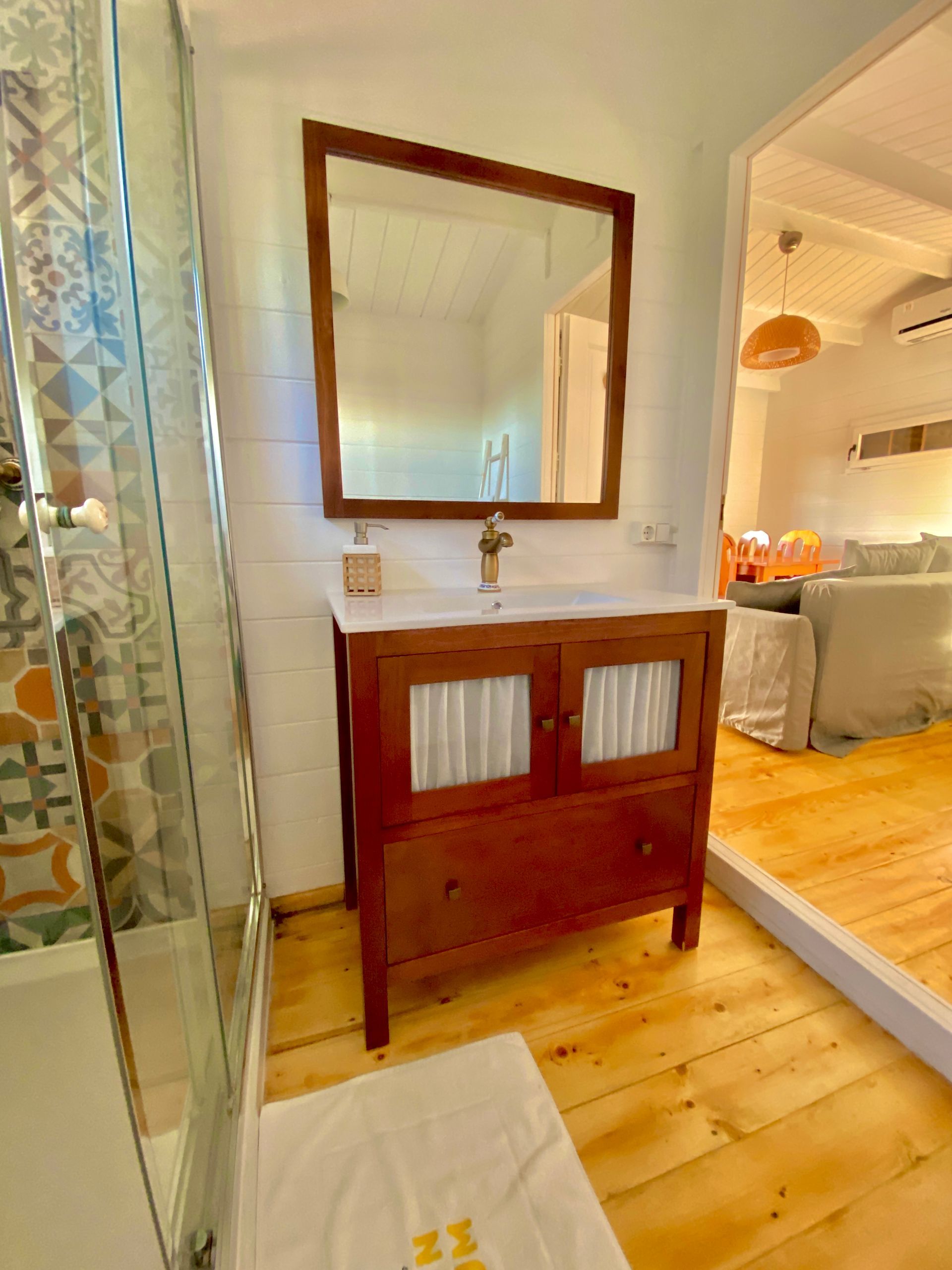 A bathroom with a sink , mirror , and wooden floor.