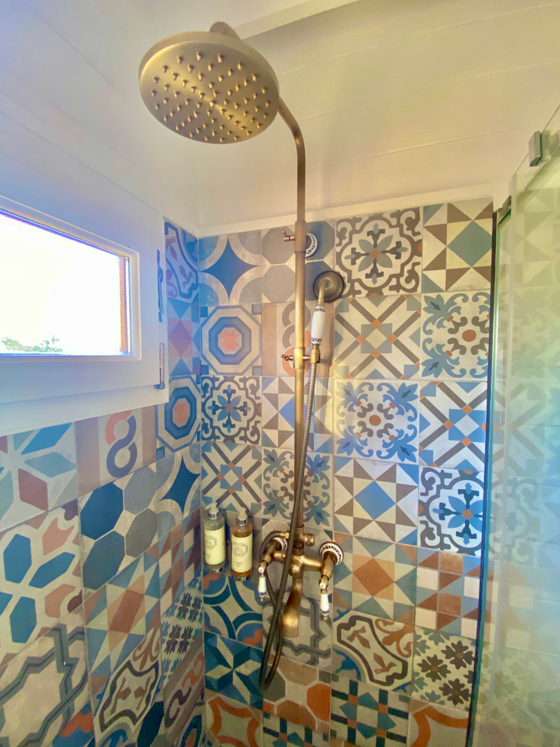 A shower with colorful tiles and a shower head.