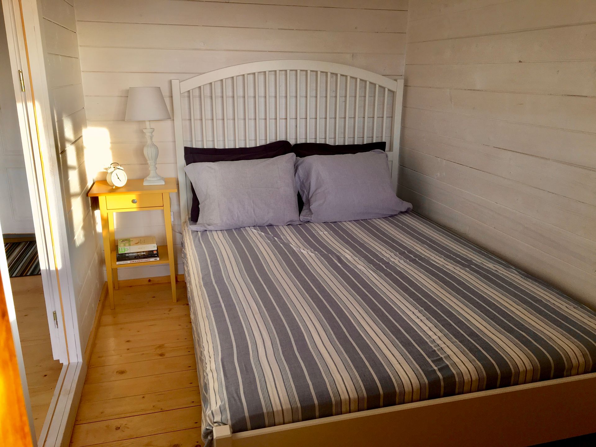 A bedroom with a bed and a nightstand with a lamp