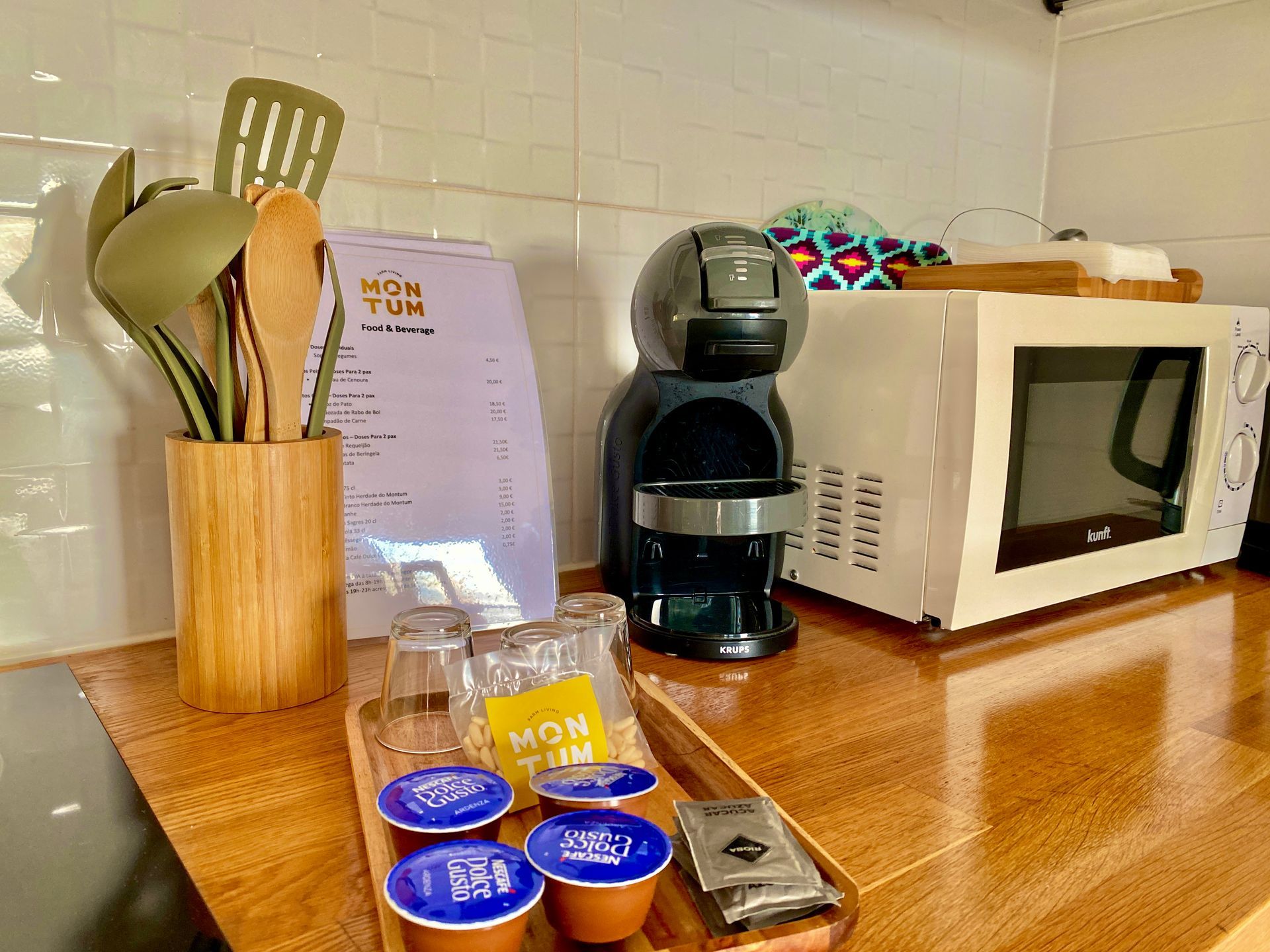 A kitchen counter with a coffee maker , microwave , and utensils.