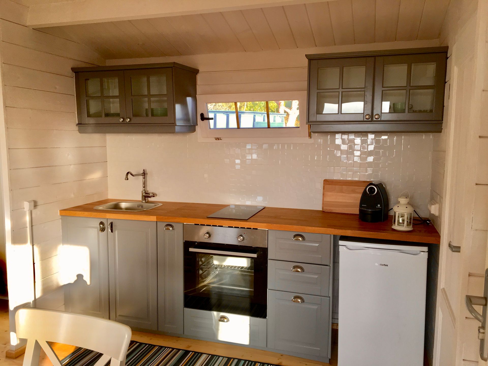 A kitchen with gray cabinets and a white refrigerator
