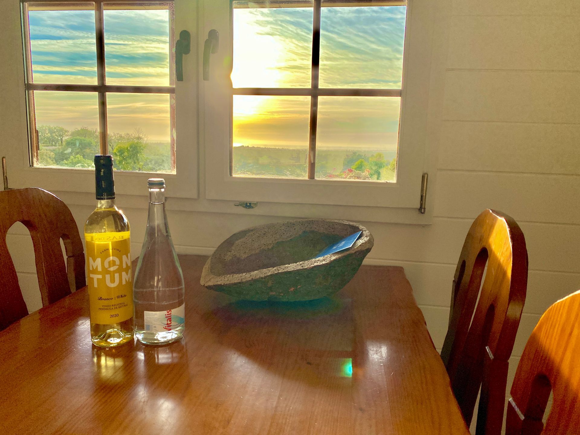 A bottle of mon tun sits on a wooden table in front of a window