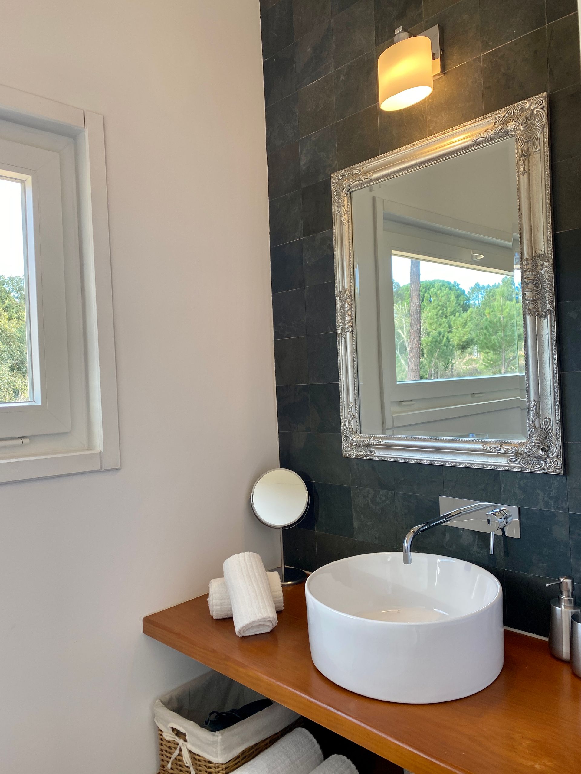 A bathroom with a sink , mirror and window