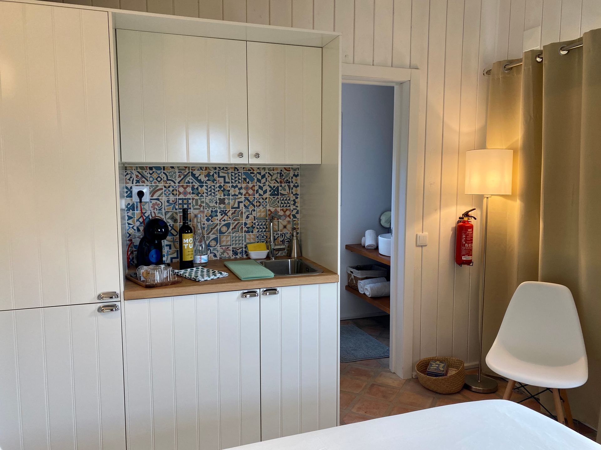 A kitchen with white cabinets and a fire extinguisher on the wall