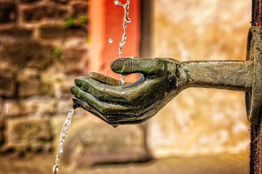 A statue of a hand holding water from a fountain.