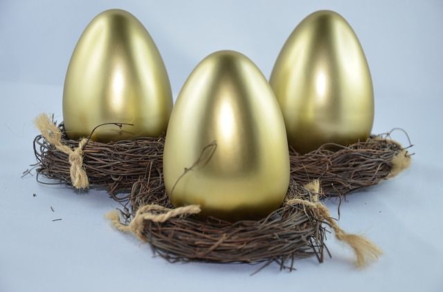 Three gold eggs are sitting in a nest.