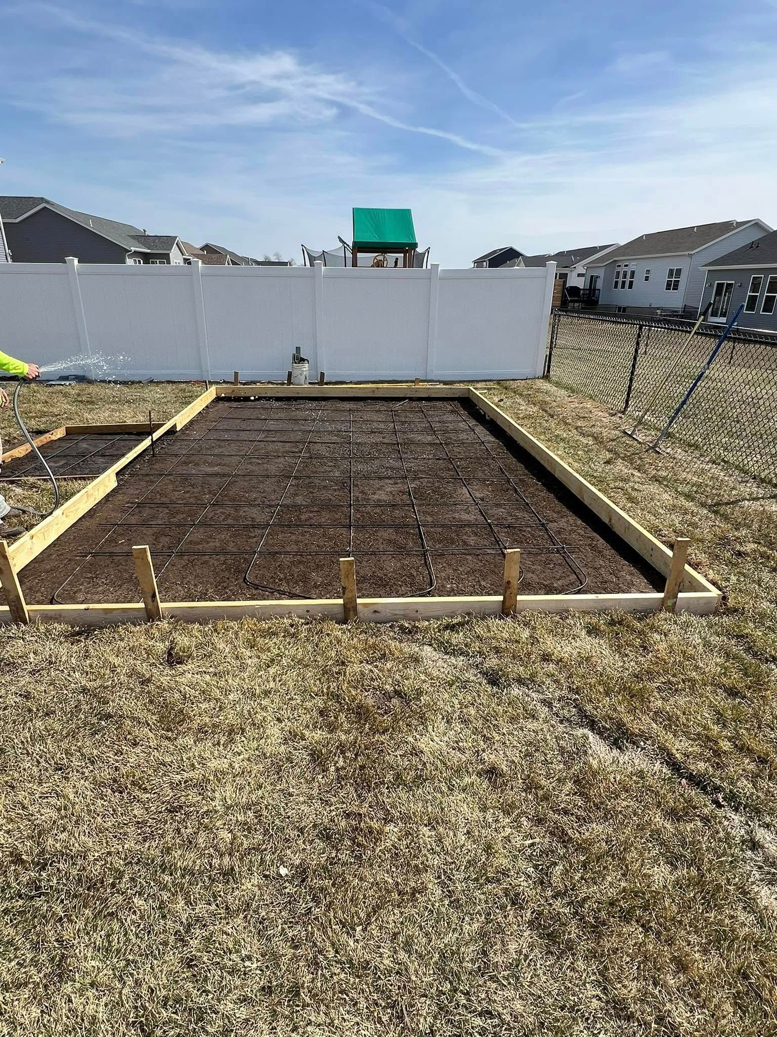 Raised garden bed with soil, wooden frame, and grid, in a backyard.