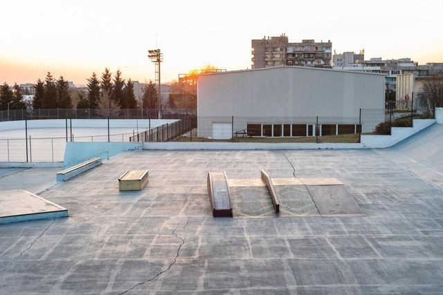 Snow-covered rooftop with benches at sunset beside a large white building