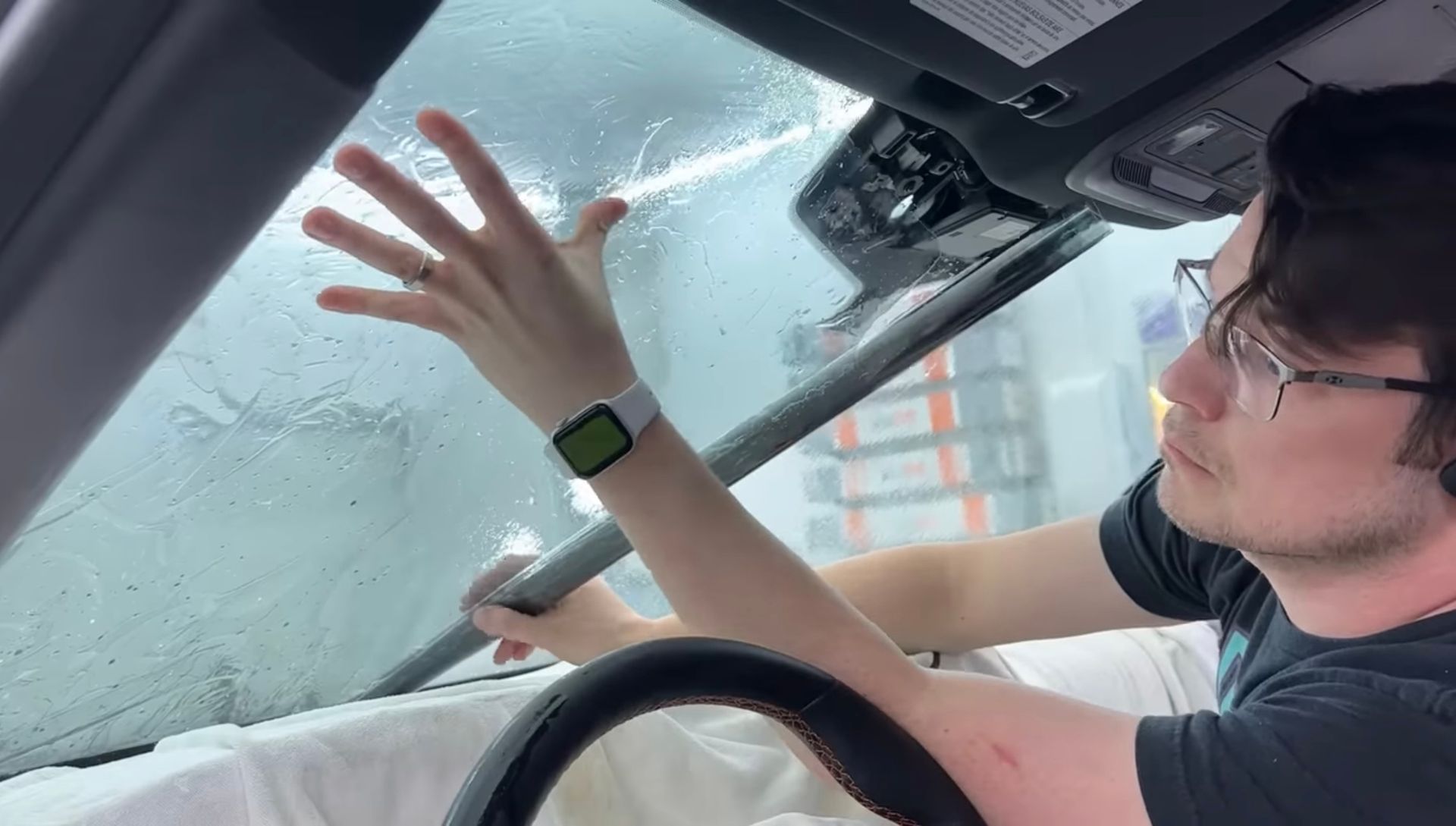 A man is cleaning the windshield of a car.