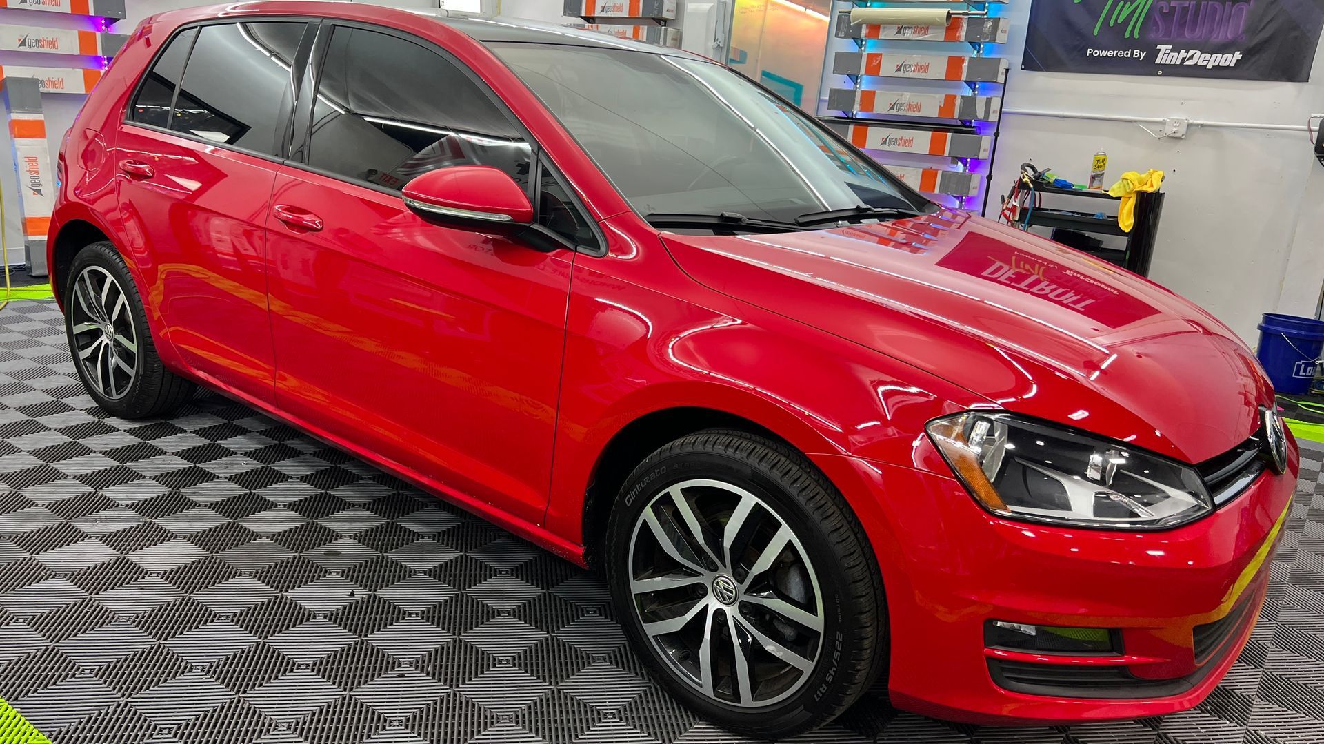 A red volkswagen golf is parked in a garage.