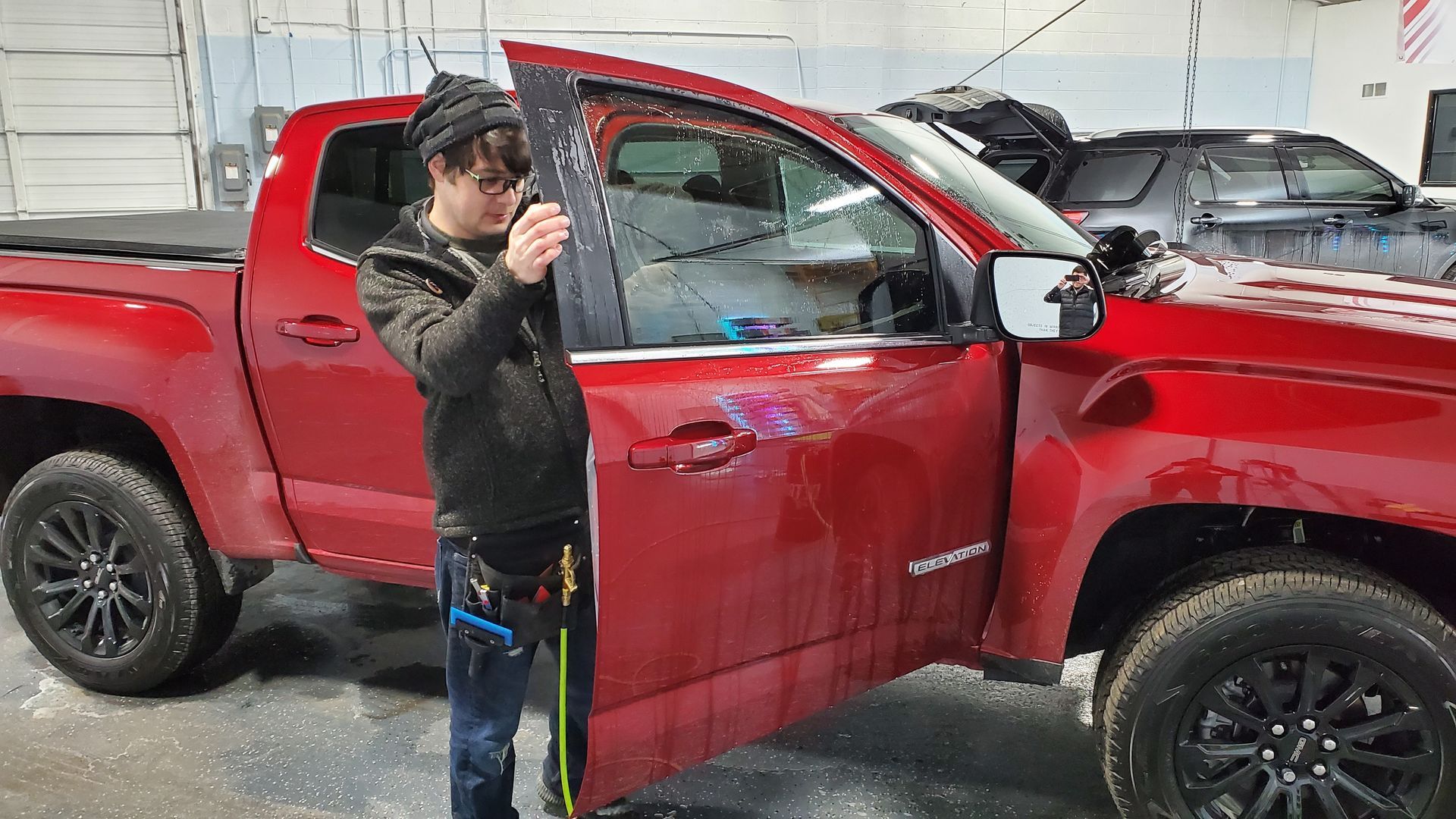 A man is standing next to a red truck in a garage.