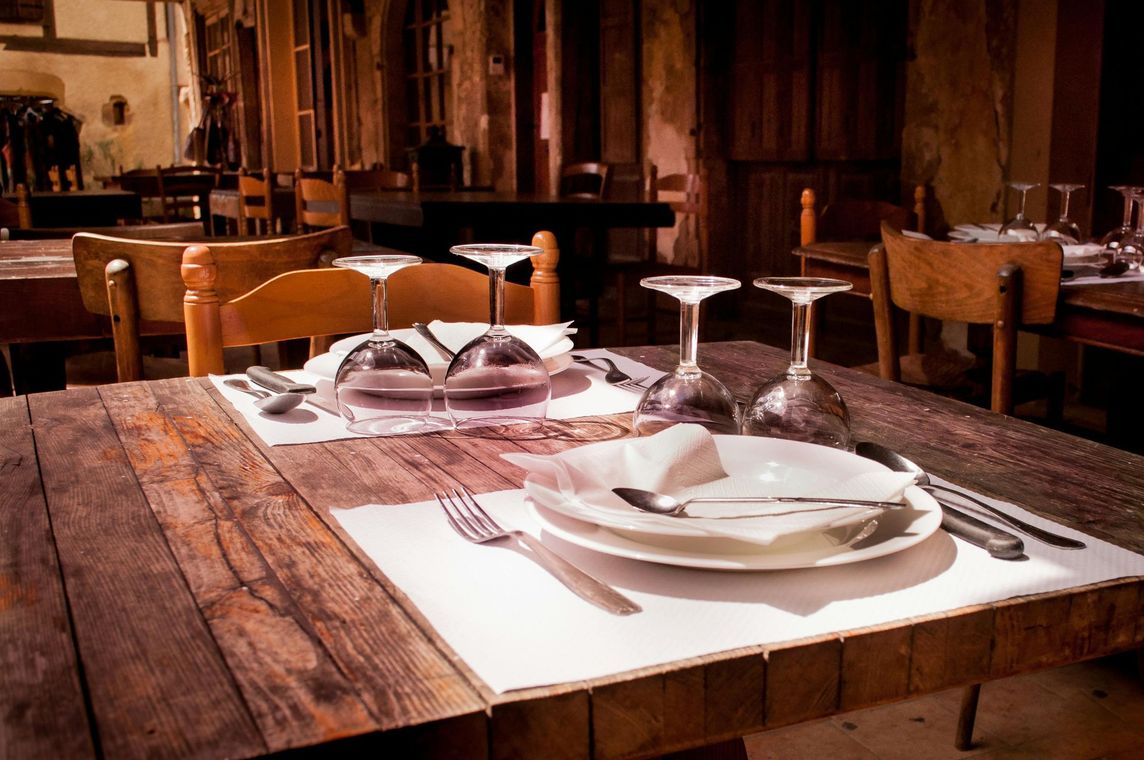 Set table with plates and wine glasses on a rustic wooden restaurant table